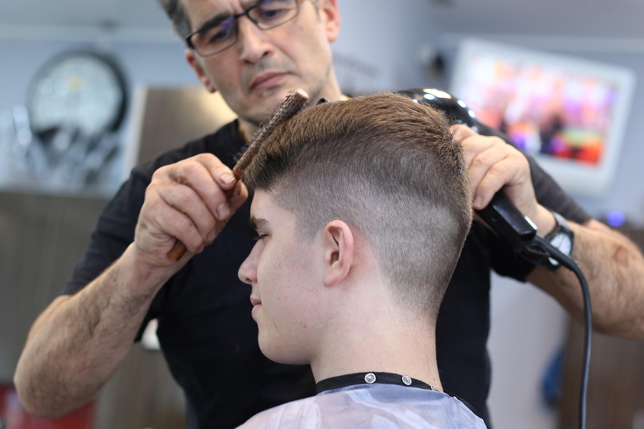 A stylist cutting a client's hair with comb and scissors