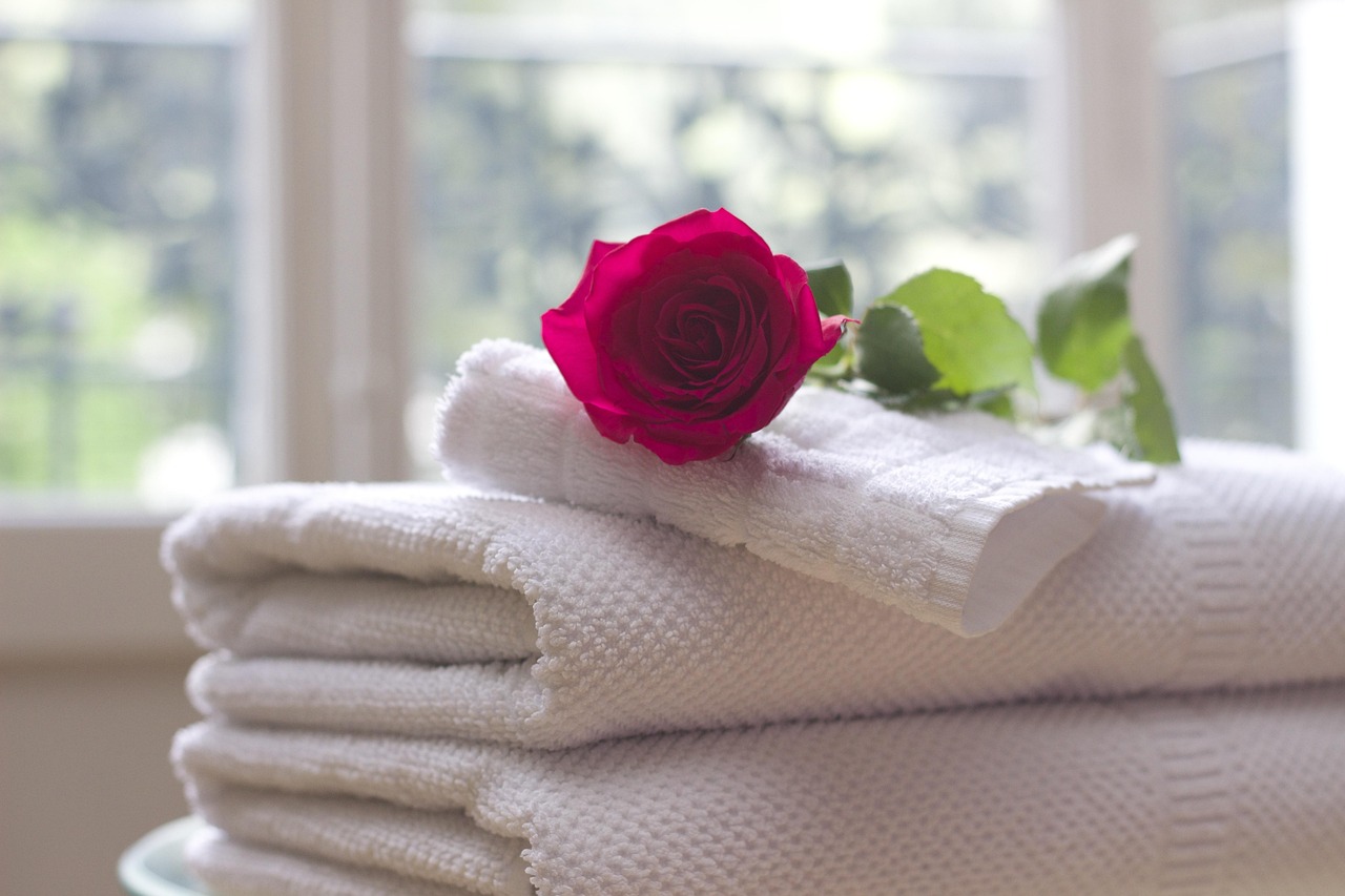 Folded white towels with a rose
