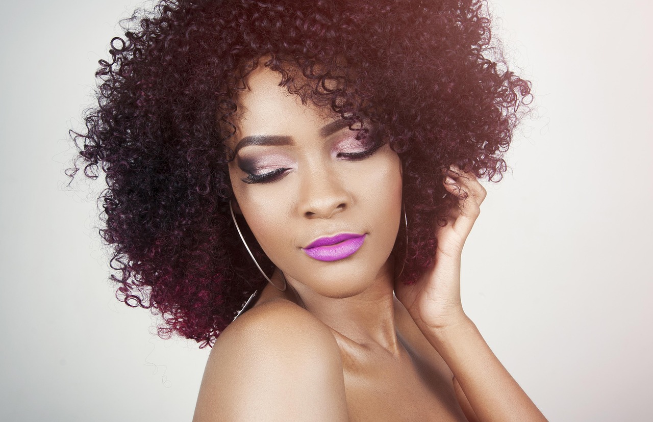 A woman with glossy curly hair and polished makeup, smiling